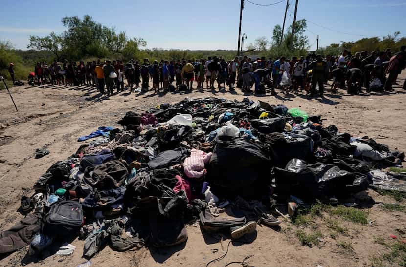 Migrants stands near a pile of discarded items as they wait to be processed by the U.S....