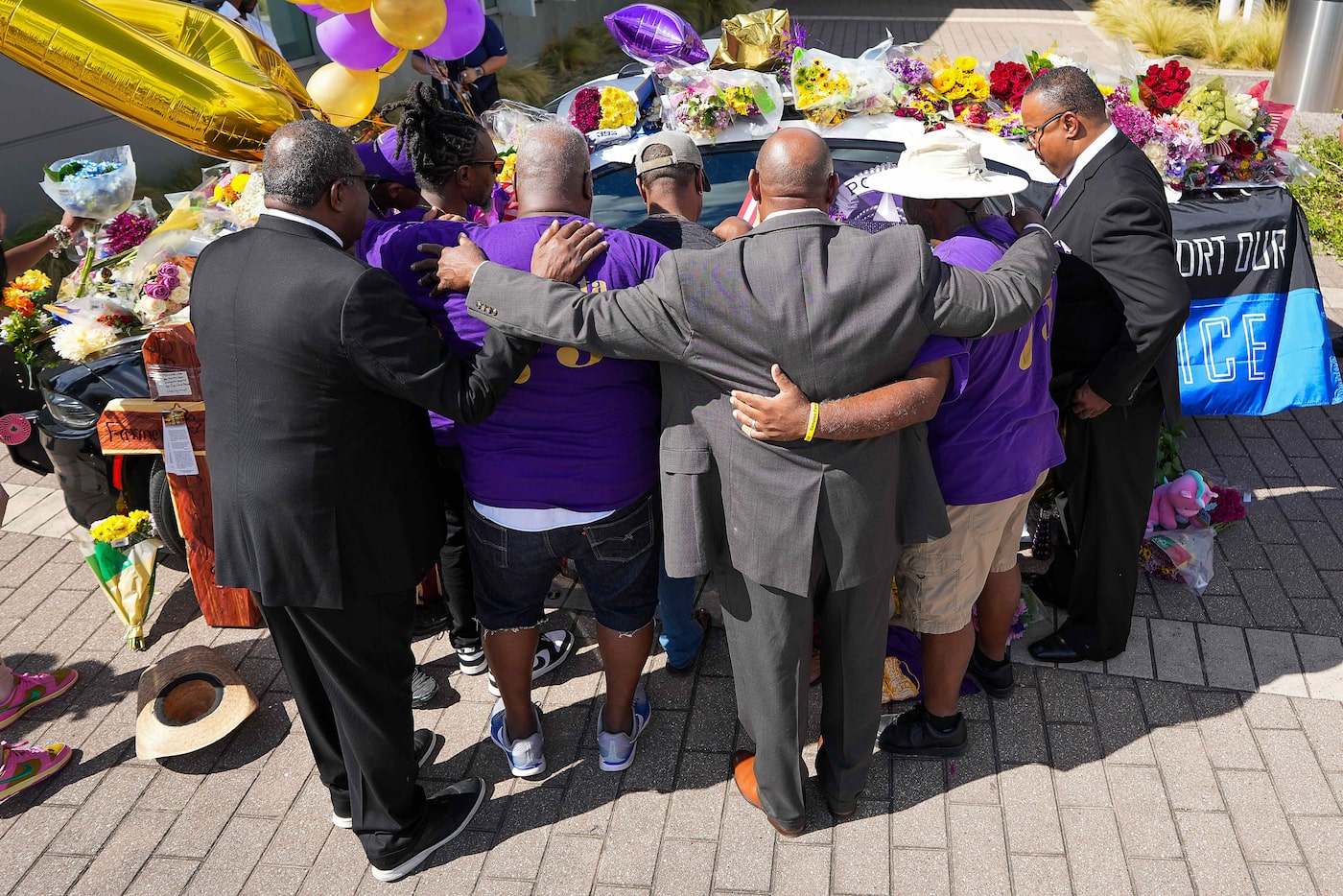 Fellow fraternity bothers gather in prayer around a Dallas police patrol car serving as a...