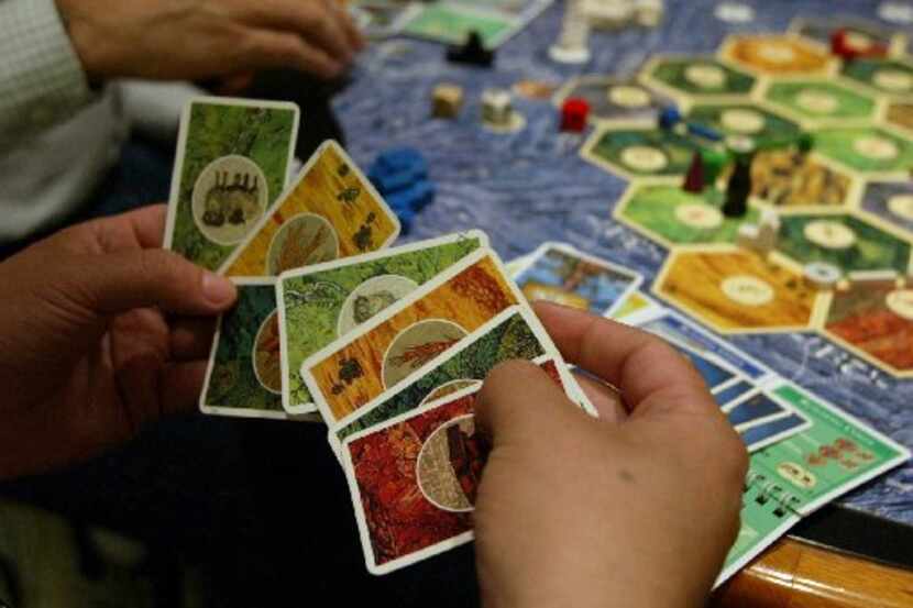 John Baxter of Dallas looks over his cards in the game 'Settlers of Catan'. while playing ...