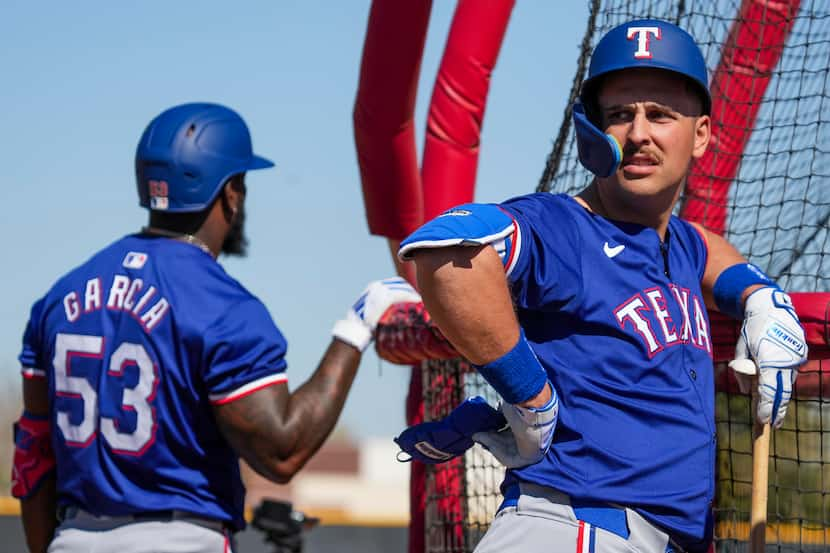 Texas Rangers infielder Nathaniel Lowe and outfielder Adolis García wait to hit live batting...