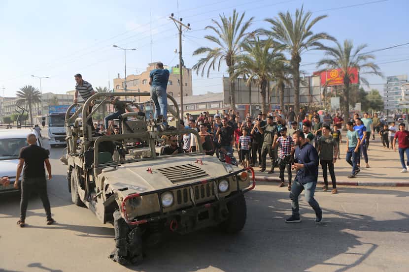 Palestinians ride on an Israeli military vehicle taken by an army base overrun by Hamas...