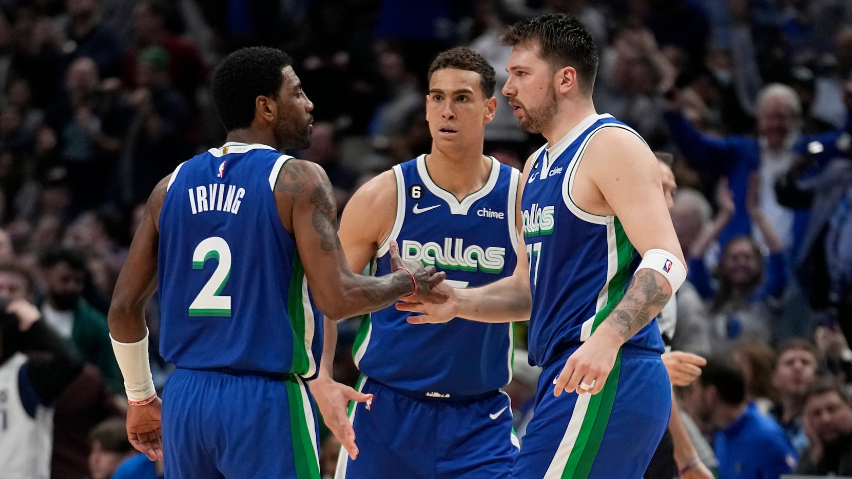 Dallas Mavericks' Kyrie Irving (2), Dwight Powell, center, and Luka Doncic, right, celebrate...
