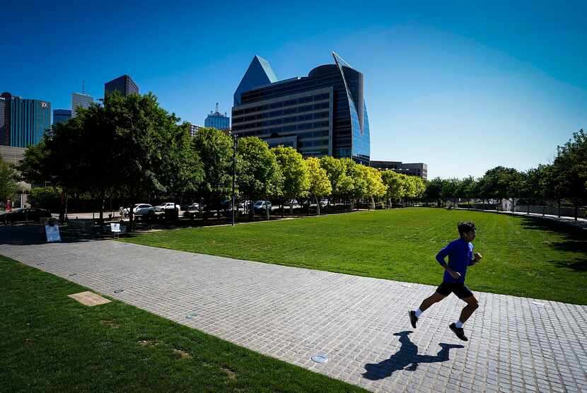 A runner has room to glide through the relatively empty Klyde Warren Park on Monday...