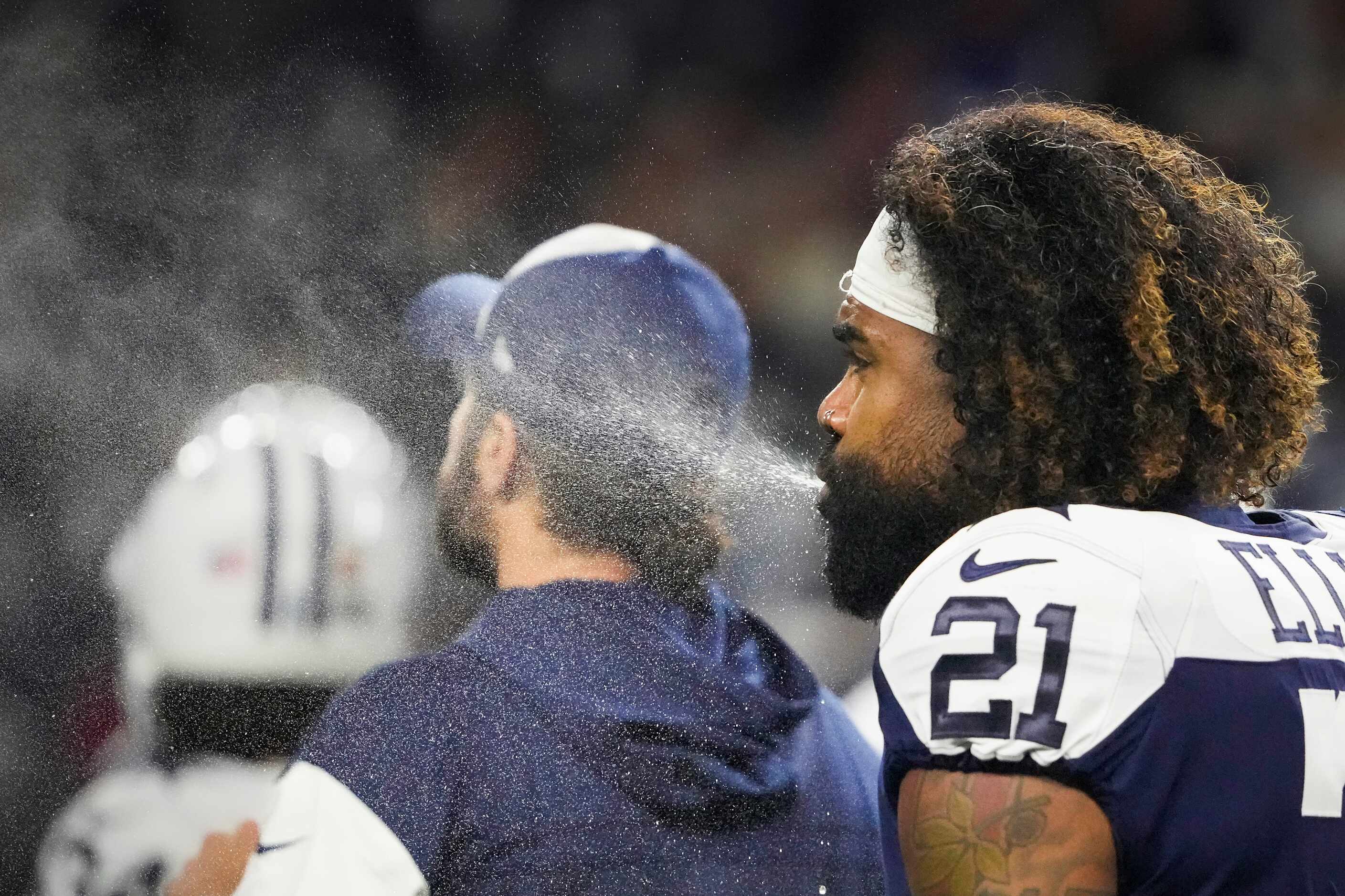 Dallas Cowboys running back Ezekiel Elliott spits water as he warms up before an NFL...