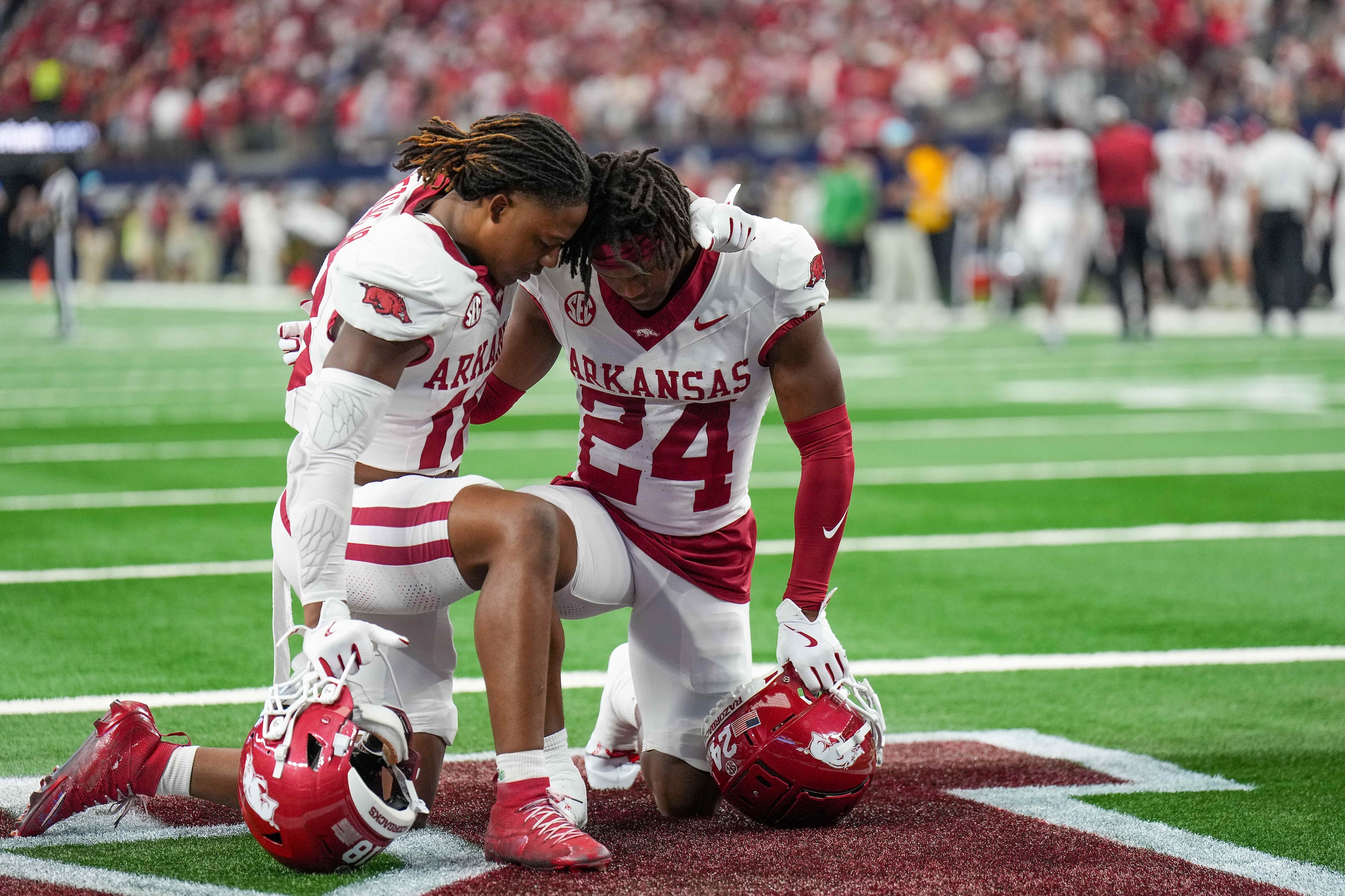 Arkansas defensive backs TJ Metcalf (18) and Tevis Metcalf (24) kneel in prayer before the...