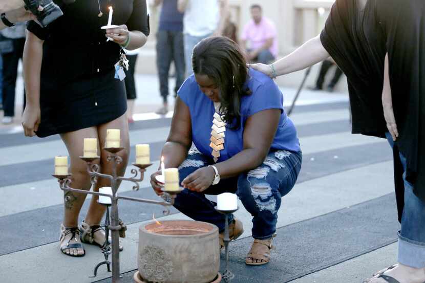 Matisha Ward, daughter of Antoinette Brown, pauses was consoled as she lit a candle during a...