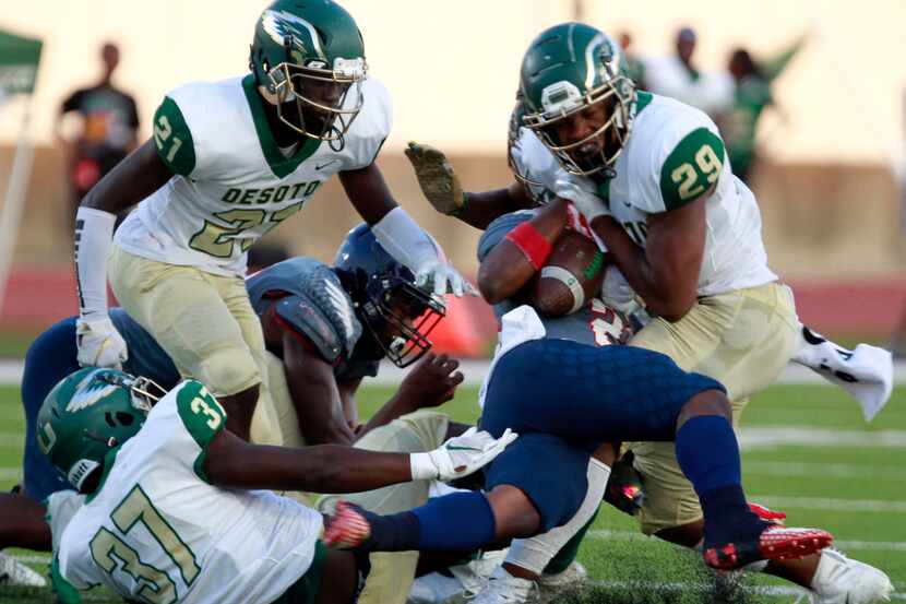 Bishop Dune RB Greg Lane (28) is twisted and tackled by several Desoto defenders, including...
