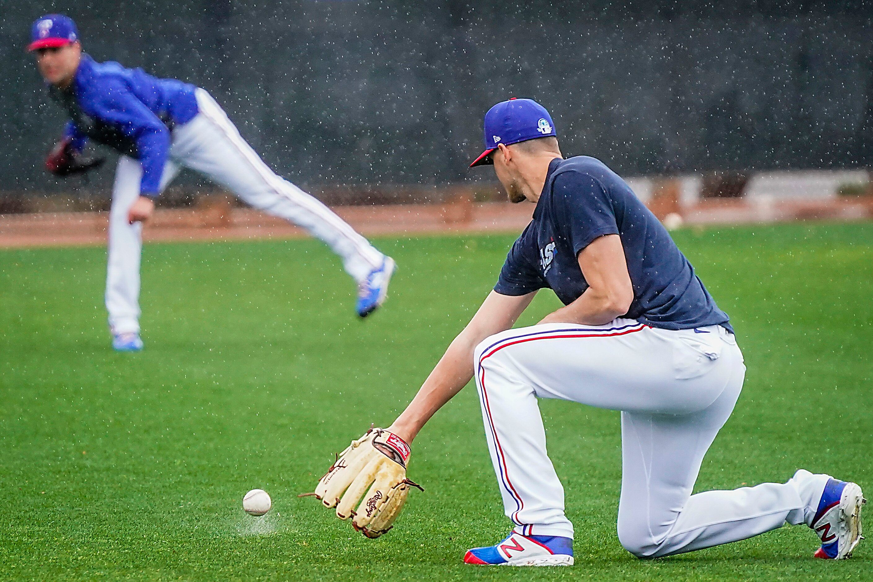 A wet ball skips past Texas Rangers pitcher Brett Martin while playing long toss with...