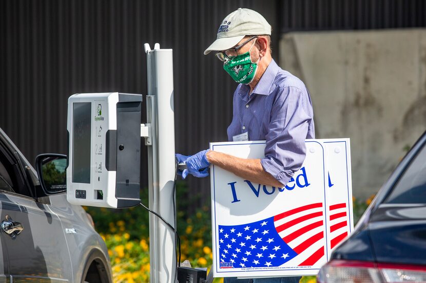 Election poll worker Daryl Hinshaw wheels a curbside voting machine to a parked voter during...