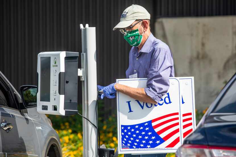 Election poll worker Daryl Hinshaw wheels a curbside voting machine to a parked voter during...