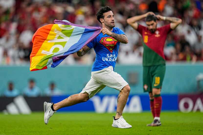 Un aficionado irrumpe en la cancha con la bandera arcoíris durante el partido del Grupo H...