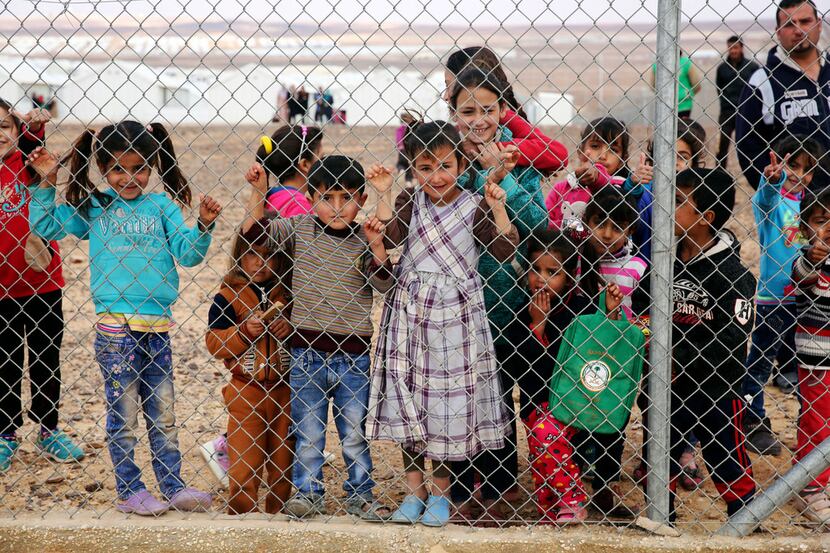 Syrian refugee children gather behind a fenced-off area of the Azraq camp for Syrian...