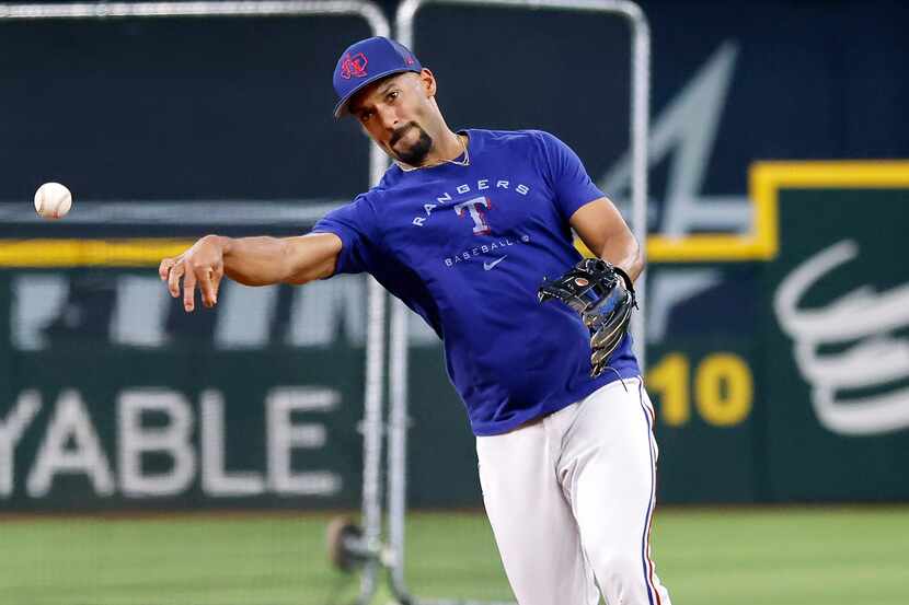 Texas Rangers second baseman Marcus Semien hurls the ball to first during batting practice...