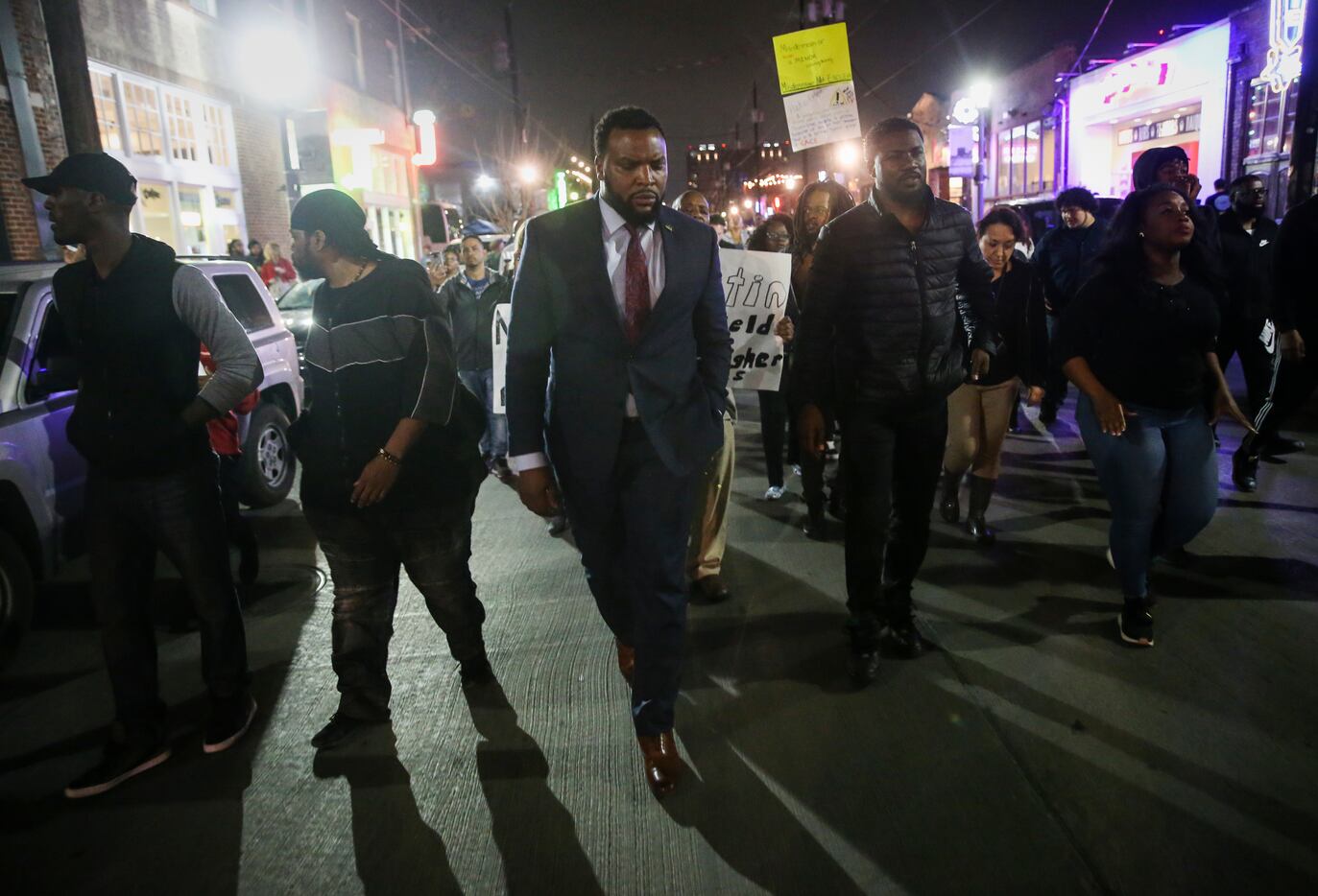 Attorney Lee Merritt, center with dress tie, joins demonstrators march through the street...