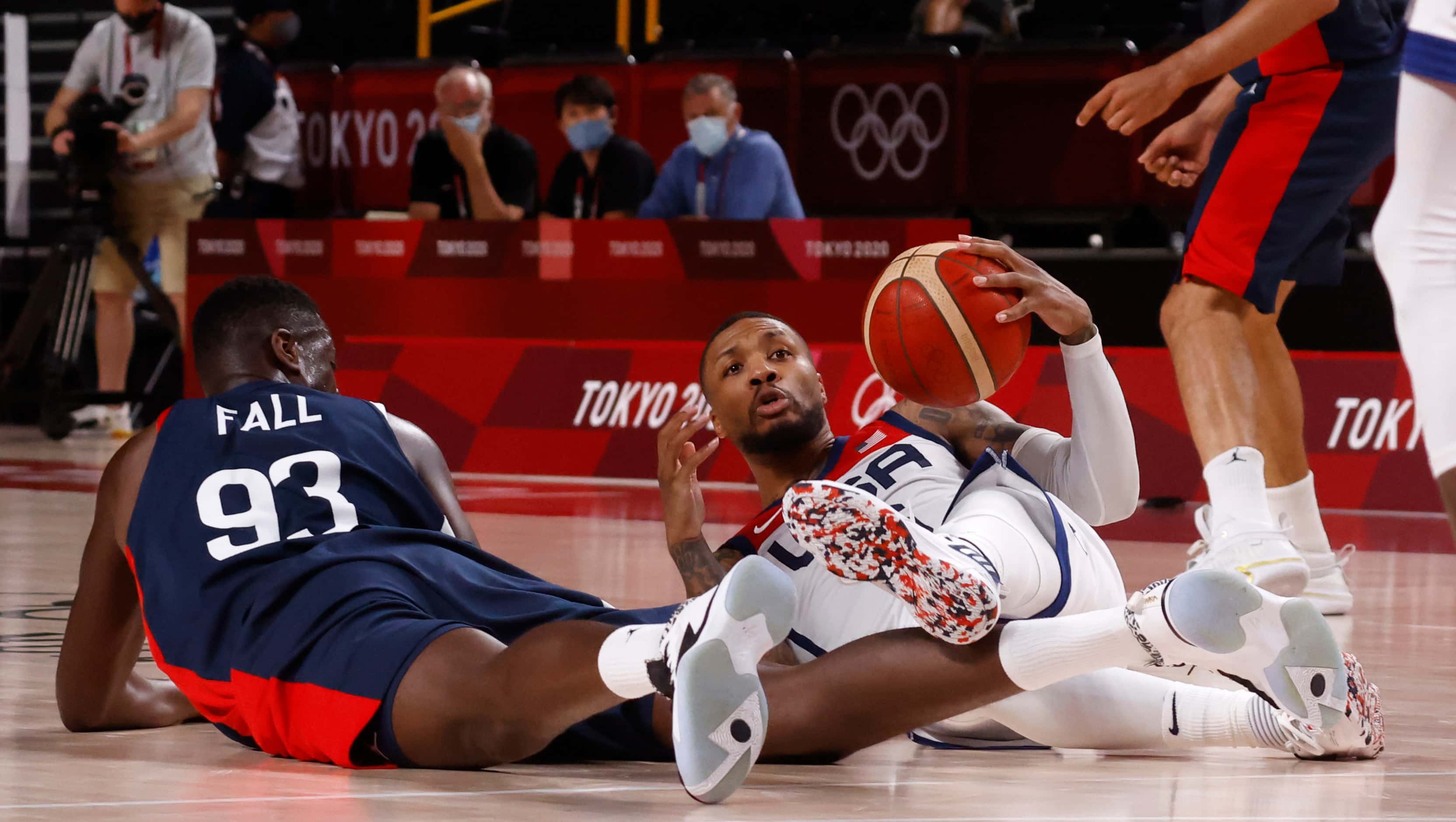 USA’s Damian Lillard (6) looks to pass the ball after diving to the floor next to France’s...