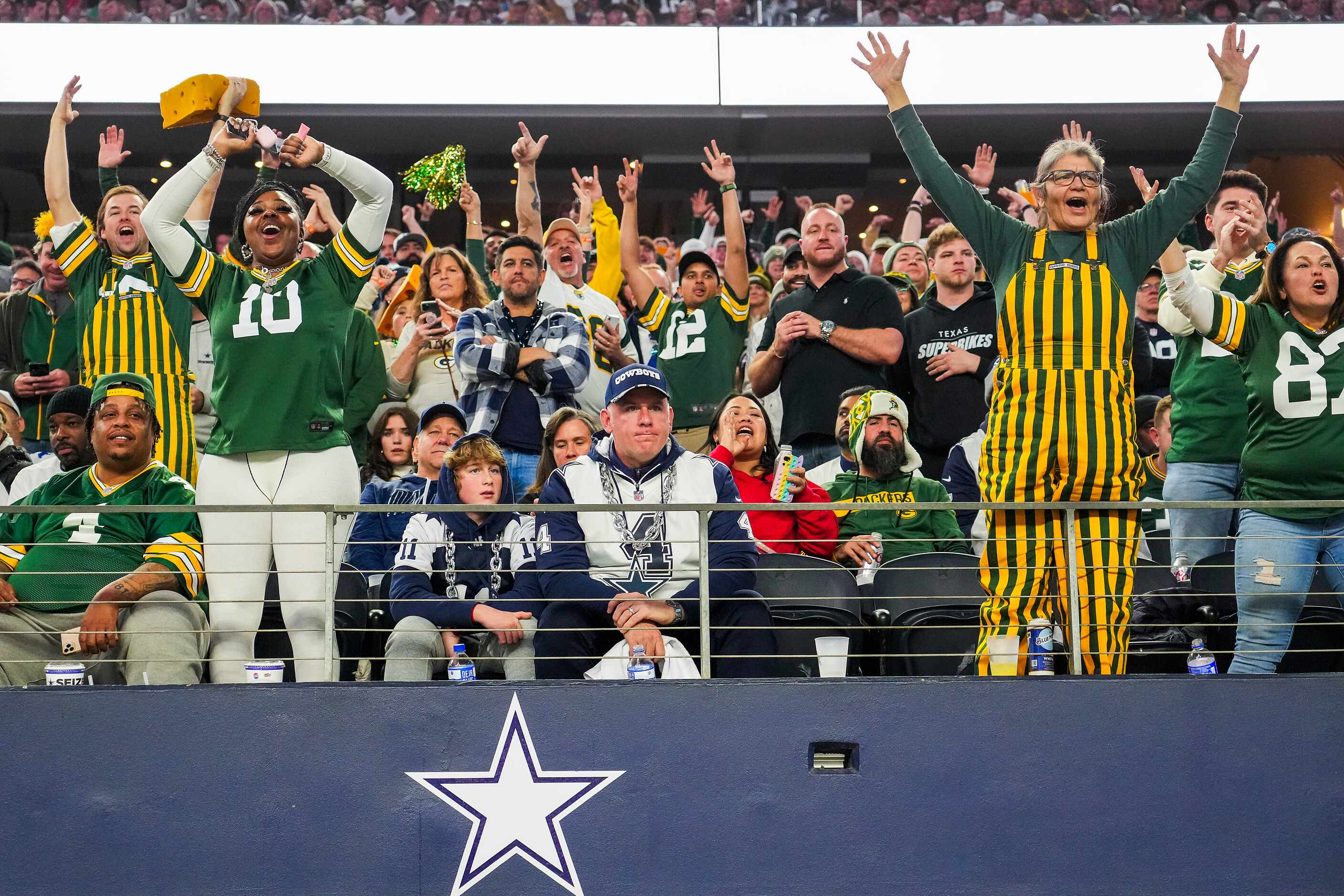 Dallas Cowboys fans sit silently as Green Bay Packers fans celebrate after a touchdown  by...