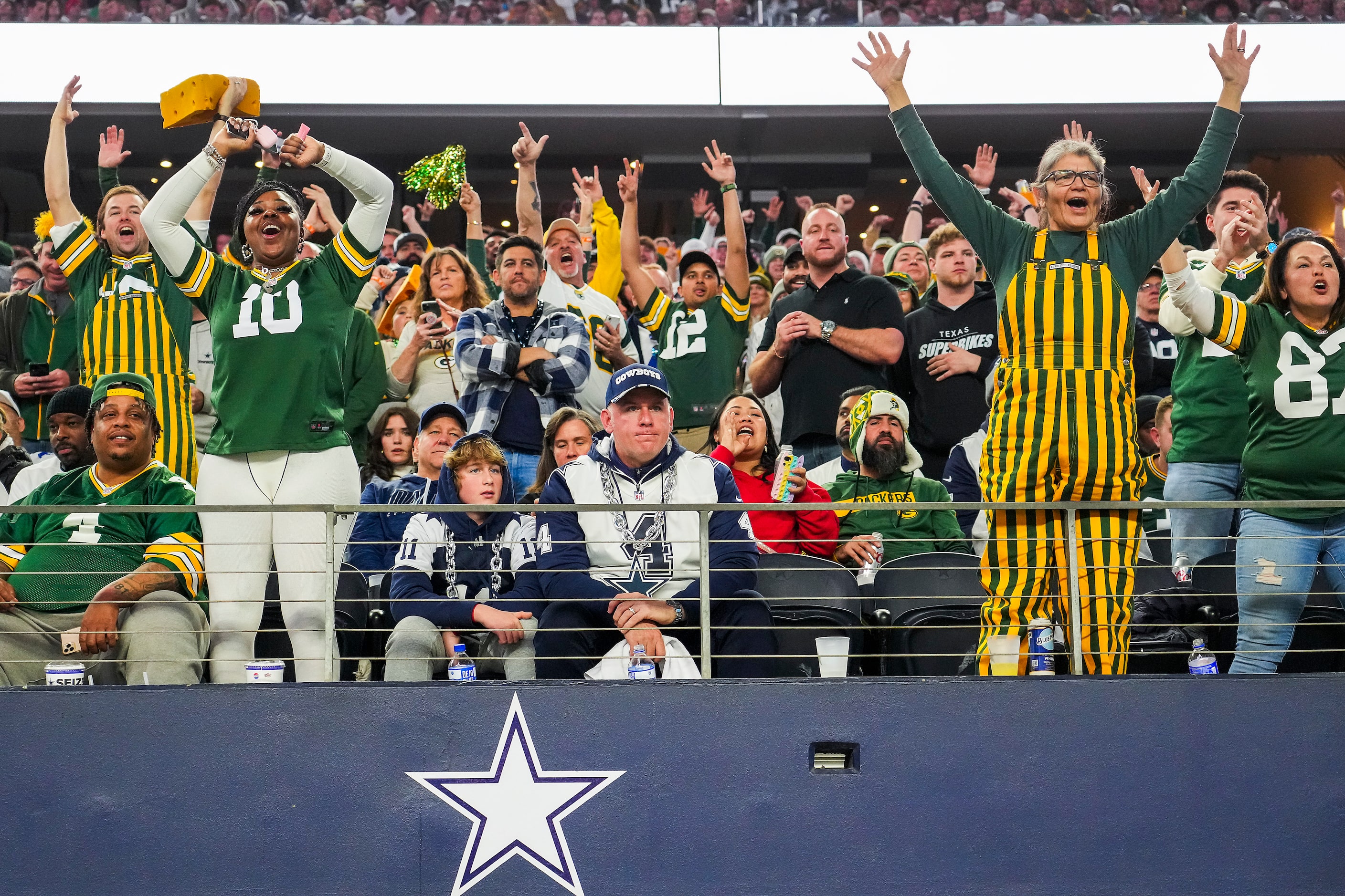 Dallas Cowboys fans sit silently as Green Bay Packers fans celebrate after a touchdown  by...