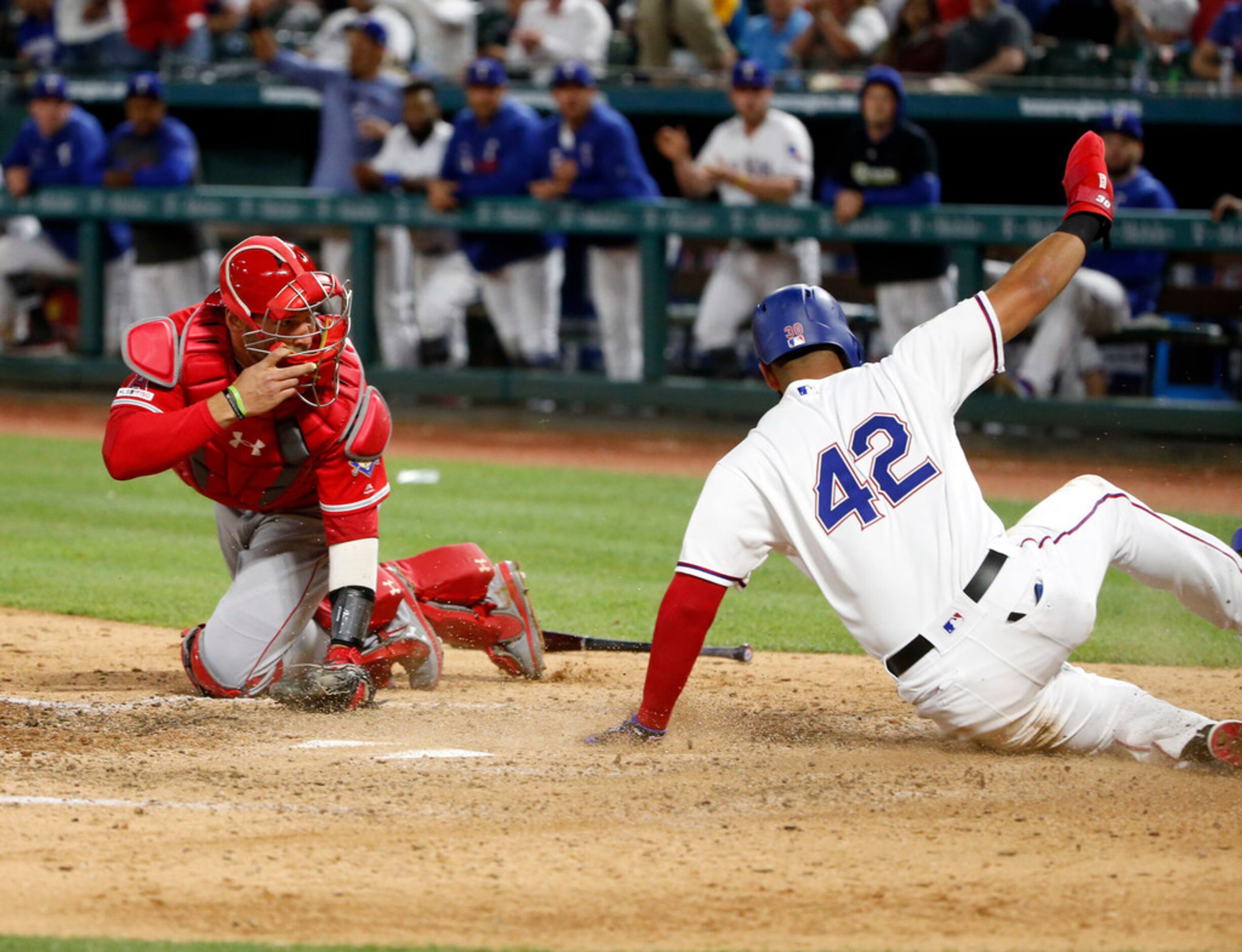 The ball gets past Los Angeles Angels catcher Kevan Smith, left, as Texas Rangers' Nomar...