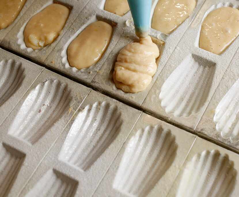 Basic lemon madeleines are piped into molds.
