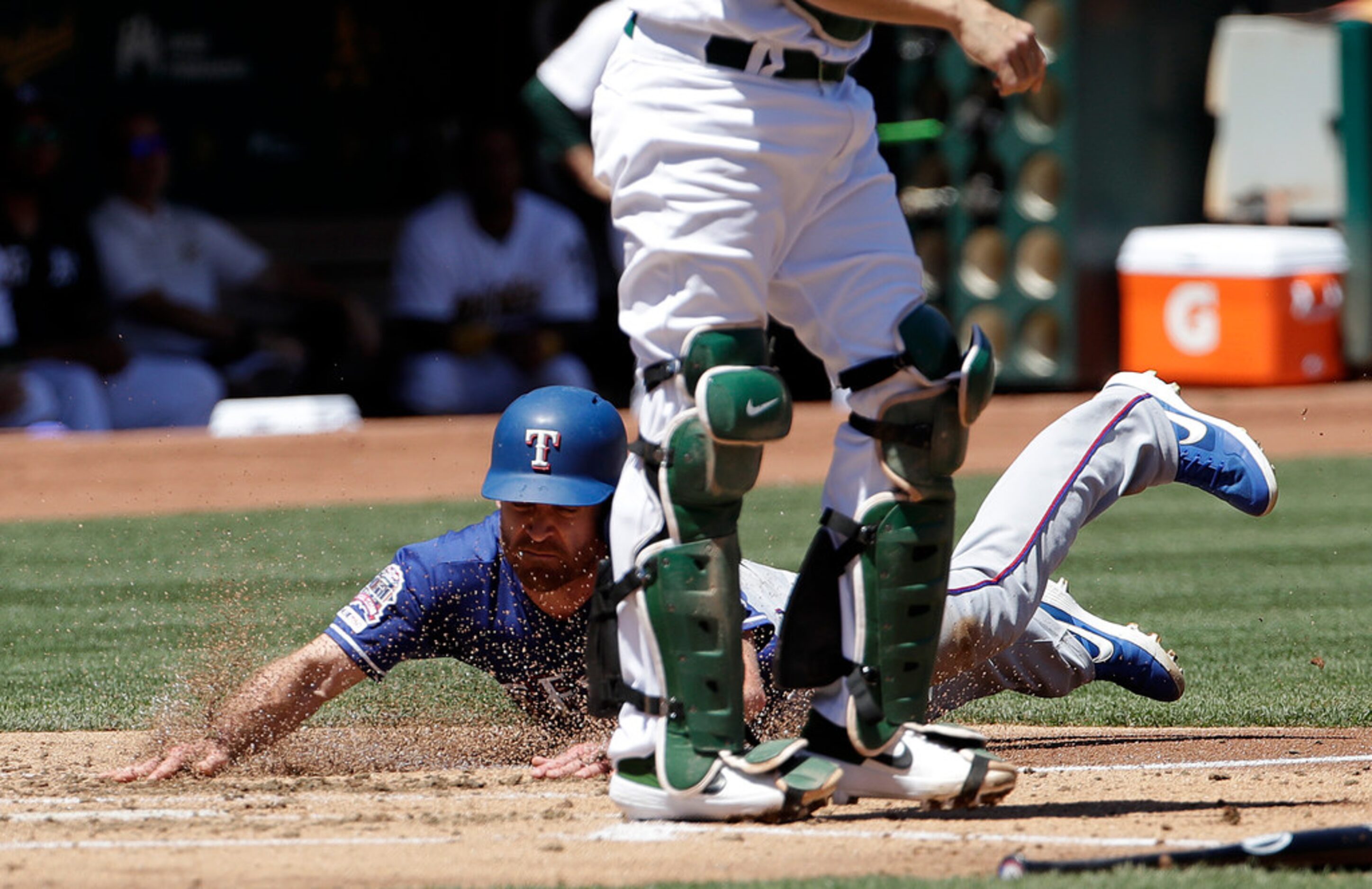 Texas Rangers' Logan Forsythe scores a run under Oakland Athletics catcher Nick Hundley...