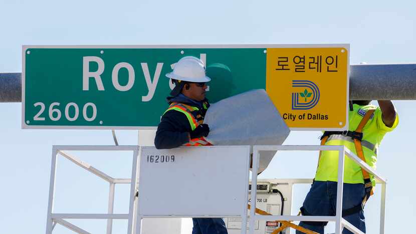 City of Dallas sign and marking technician Jose Correa removes a cover to unveil a new...