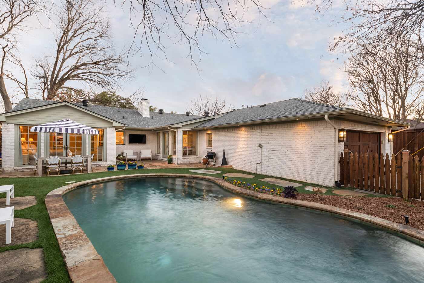 A home has a large pool with a sunbathing area with two lounge chairs.