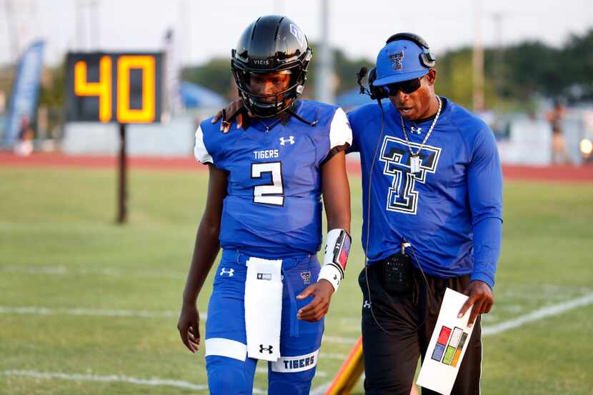 Trinity Christian-Cedar Hill offensive coordinator Deion Sanders (right), talks to his son,...