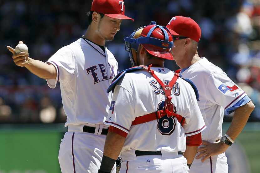 Texas Rangers pitching coach Mike Maddux (31) and catcher Geovany Soto (8) visit with...