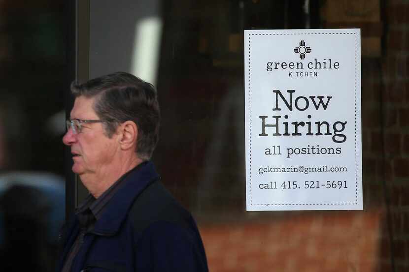 
A pedestrian walk by a now hiring sign posted in the window of a business in San Rafael,...