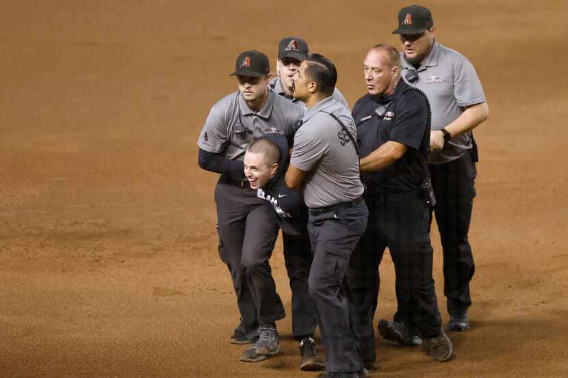 Security apprehends a fan who ran onto the field during Game 4 of the World Series between...