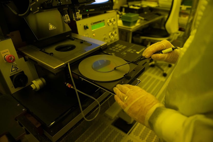 An employee handles a silicon wafer during the chips fabrication process at the Institute of...