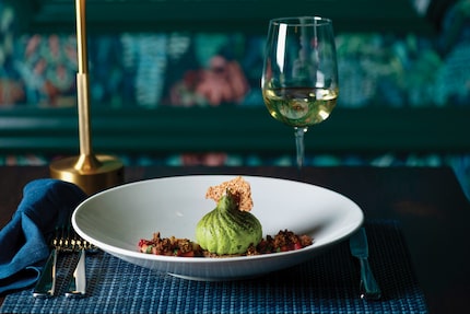 A delicate matcha cheesecake dessert in a shallow bowl resembles a bright green dumpling.