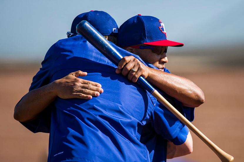 Texas Rangers third base coach Tony Beasley (facing) hugs pitcher Jake Diekman during a...