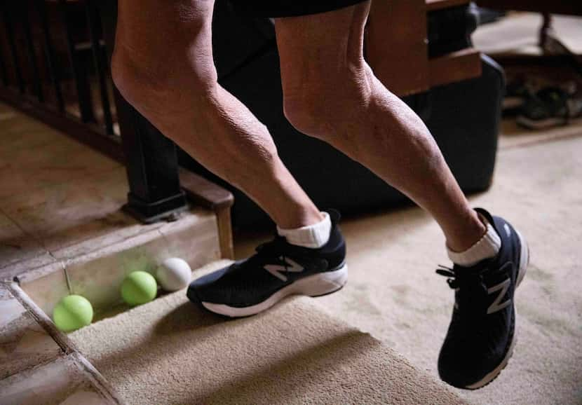 James Thruston, 84, demonstrates a stretch he does each morning before running during a...