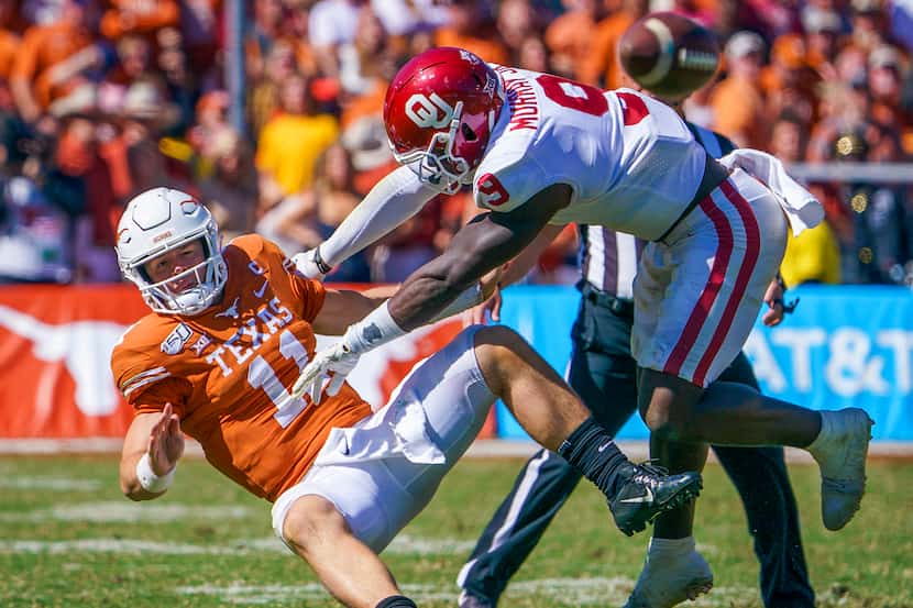 Texas quarterback Sam Ehlinger (11) is hit by Oklahoma linebacker Kenneth Murray (9) after...