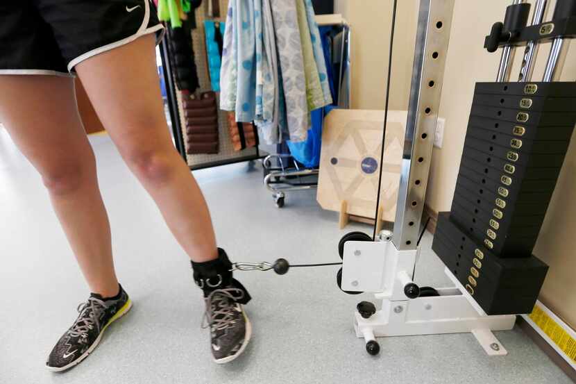 
Haley Holmes, 16, lifts a five pound weight attached to her ankle during a physical therapy...