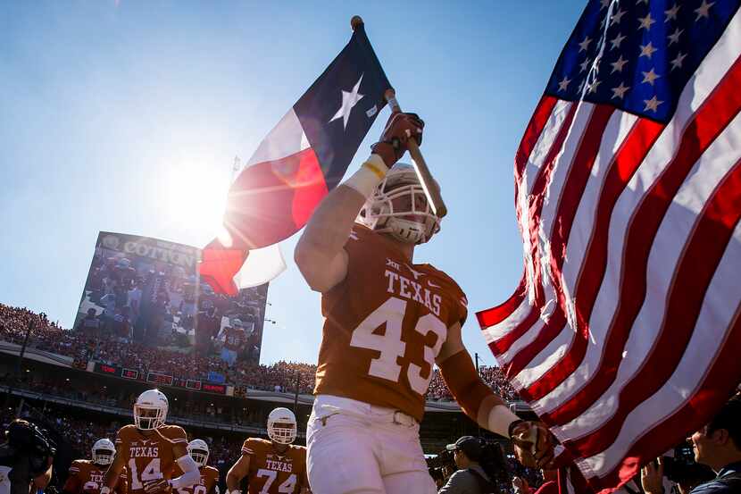University of Texas tight end Logan Mills carried the Texas flag as he led the team onto the...