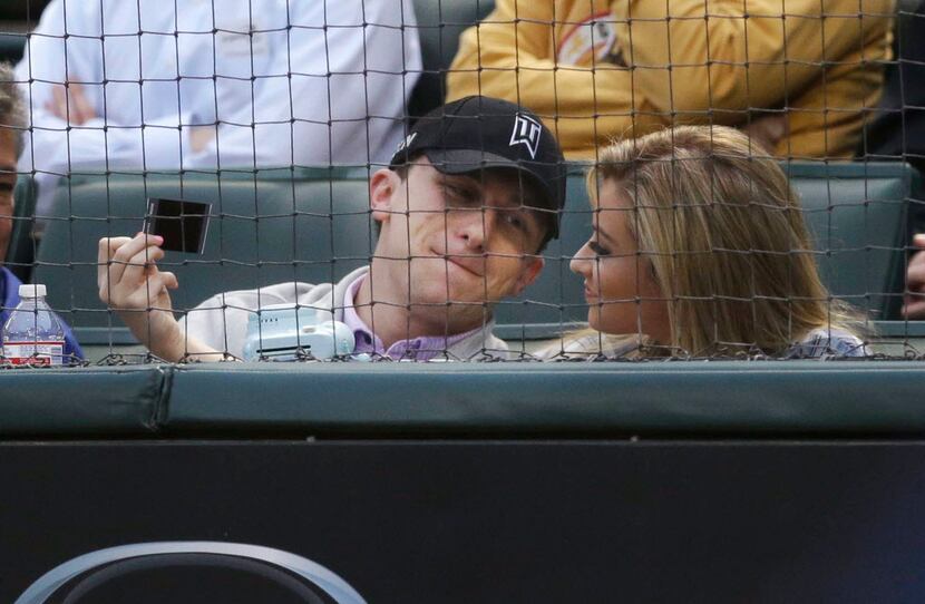 Cleveland Browns quarterback Johnny Manziel, left, sits in the stands during a baseball game...