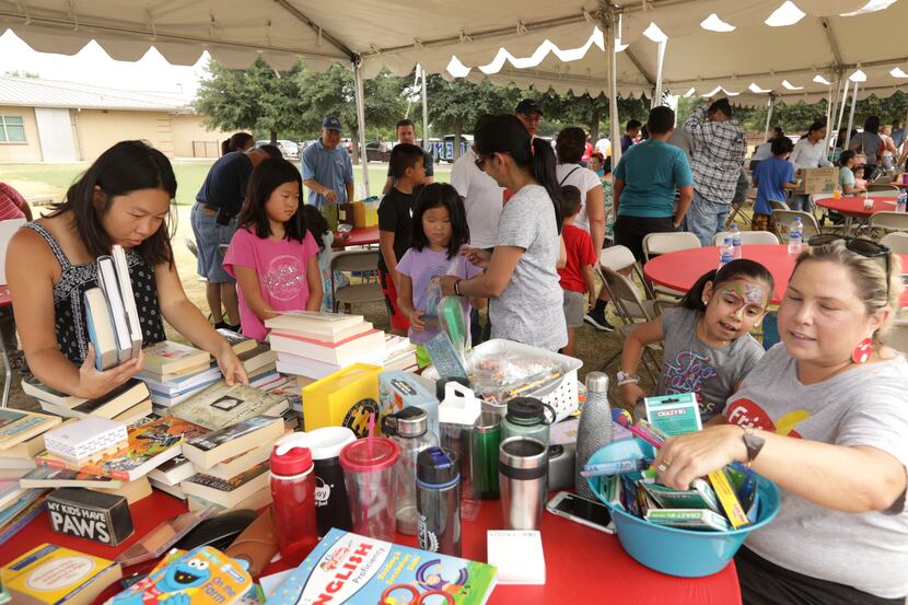 Volunteers pass out books and supplies during the Frisco Family Services Summer Lunch Grande...
