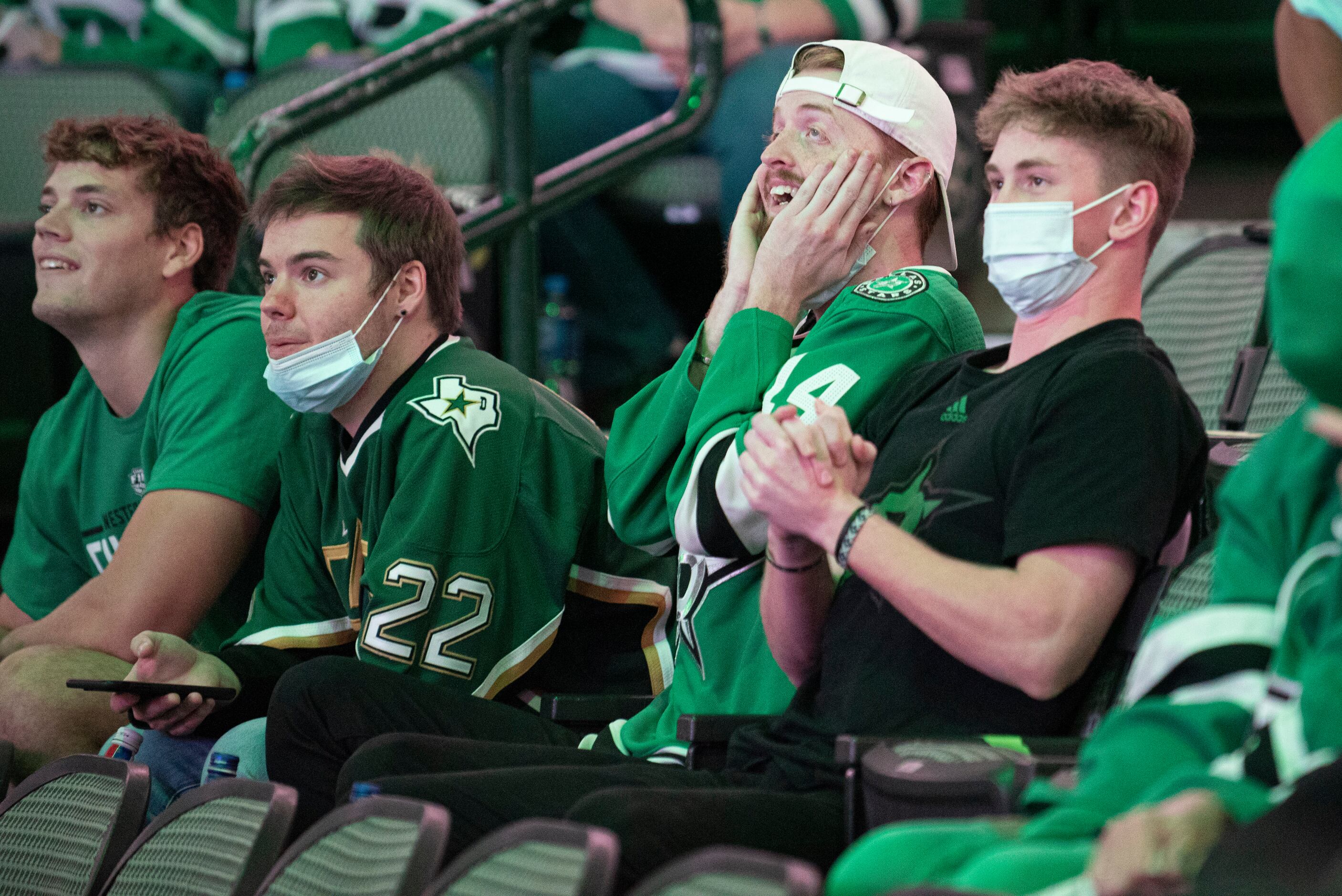 Hockey fans Casen Chase, 19, far-right, and Cooper Case, 21, at left, react to game play...
