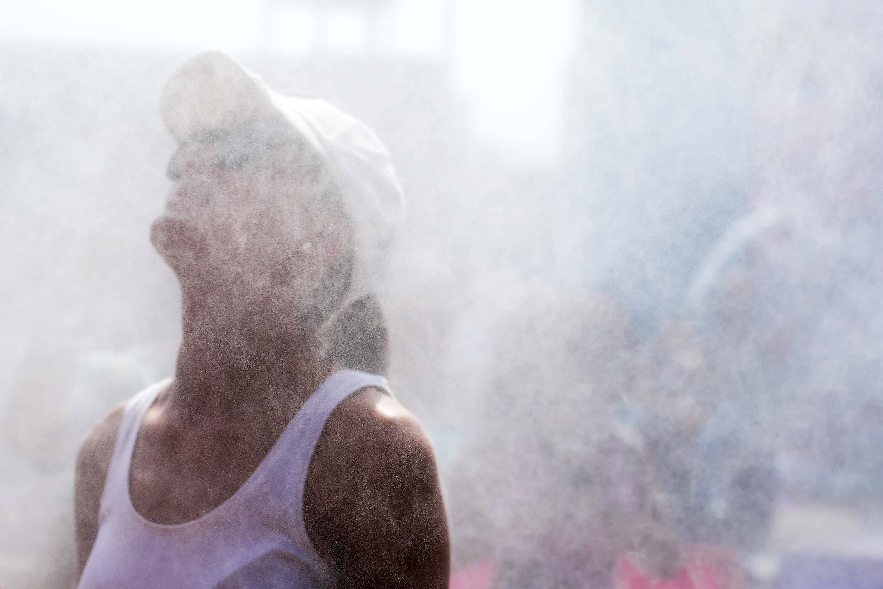 Spectators cool off under misting stations outside the 3x3 basketball venue at the 2024...