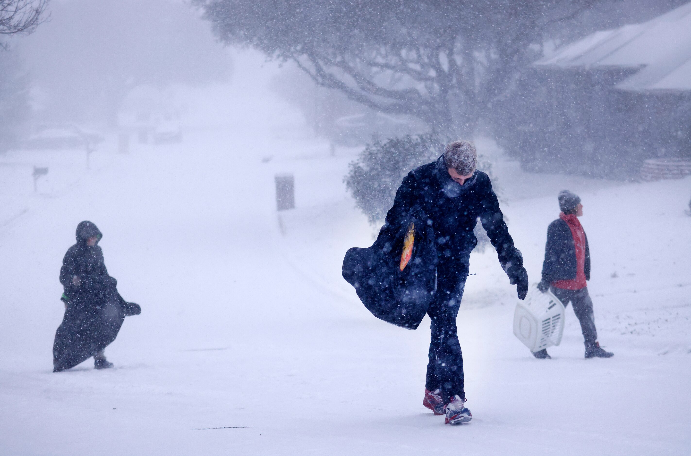 Owen Hulme (center) and his friends walk back up a steep snow-covered street in North...