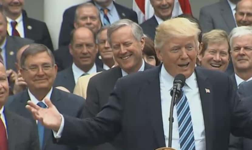 Rep. Michael Burgess (left) behind the president at a White House celebration over the House...
