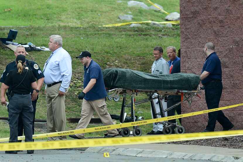 The body of the suspect is removed from a movie theater following a shooting Wednesday, Aug....