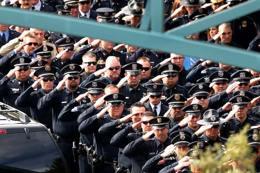 Police officers from around the area, state and country salute as the casket bearing Little...