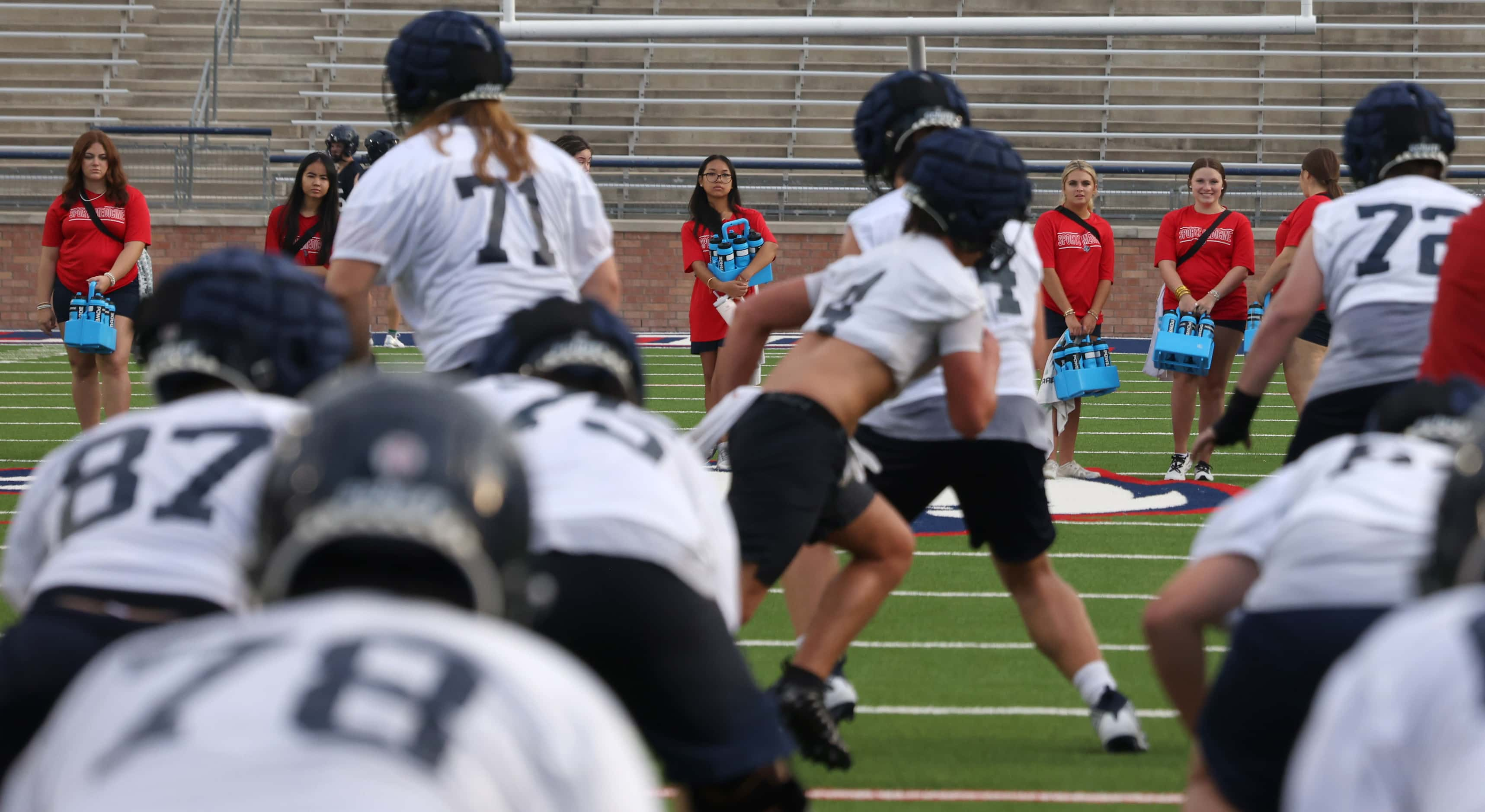 A group of Allen high school student trainers wait at midfield for hydration breaks during...