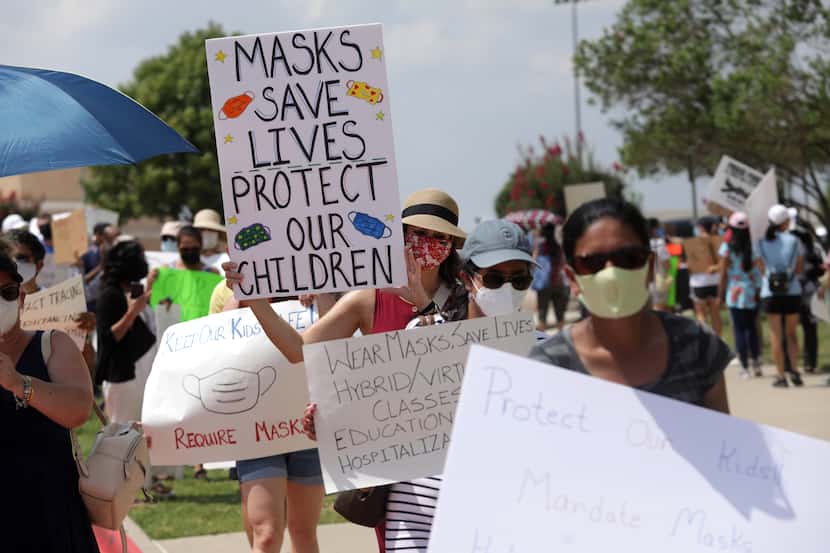 Community members seeking better COVID-19 protections gather during a protest at the Frisco...