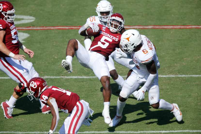  Oklahoma Sooners running back T.J. Pledger  (5) is upended by the Texas Longhorns defense...