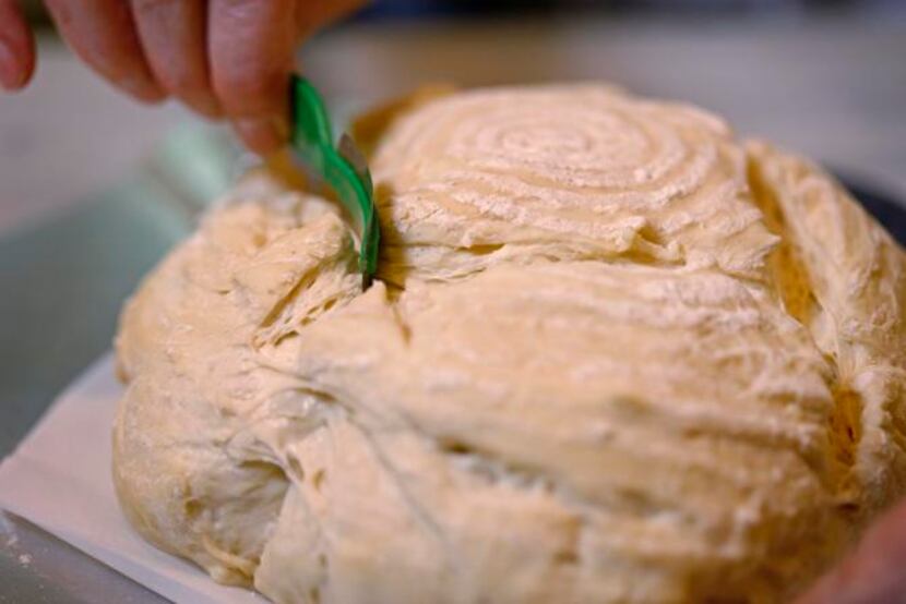 
Use a sharp, thin blade to score the surface of the dough.
