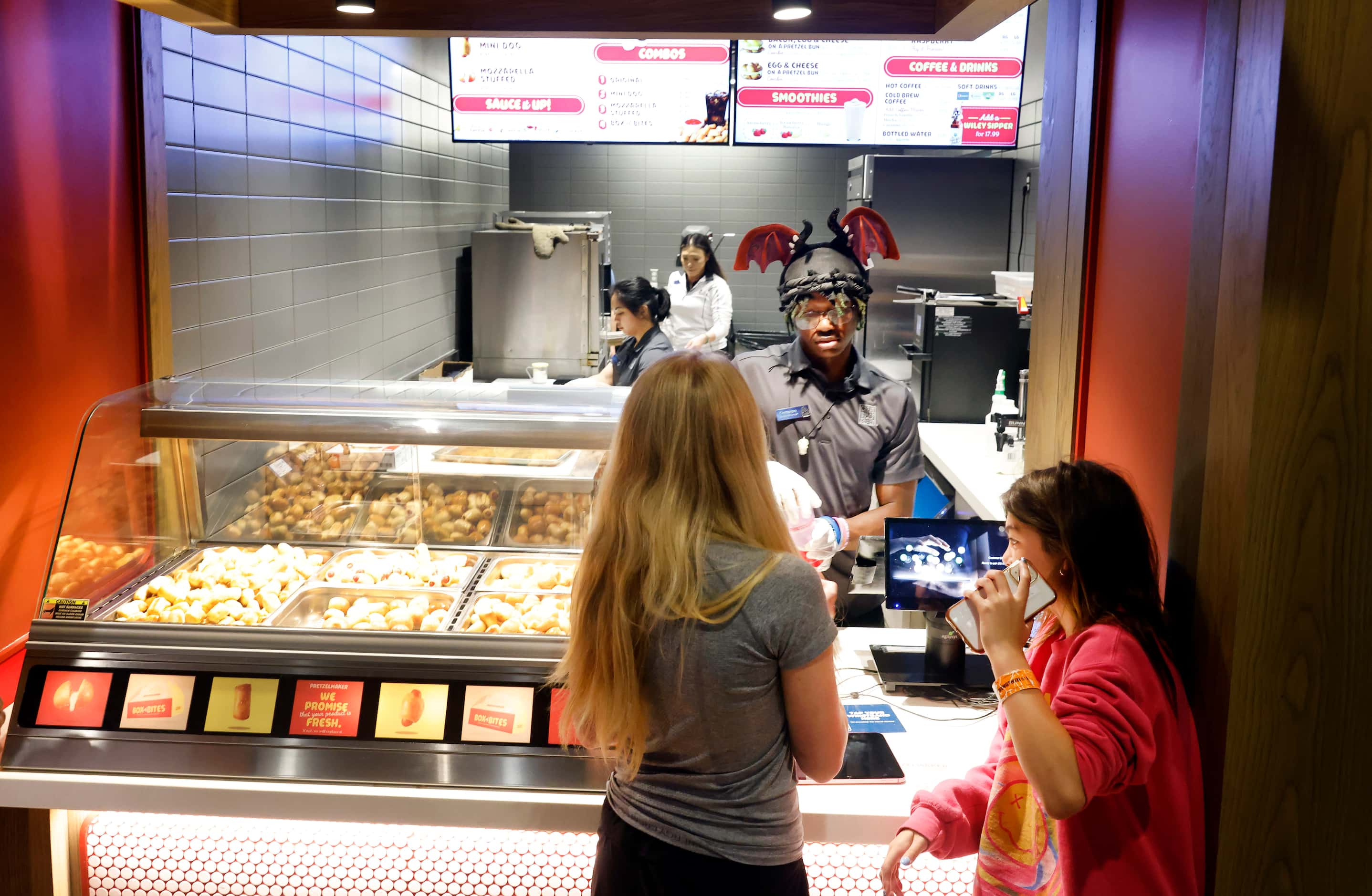 Pretzelmaker employee Cameron Ross finishes an order for teenagers at the newly opened store...